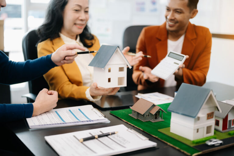 A person reviewing mortgage documents with a miniature house model and calculator on the table, symbolizing the comparison of different mortgage options.