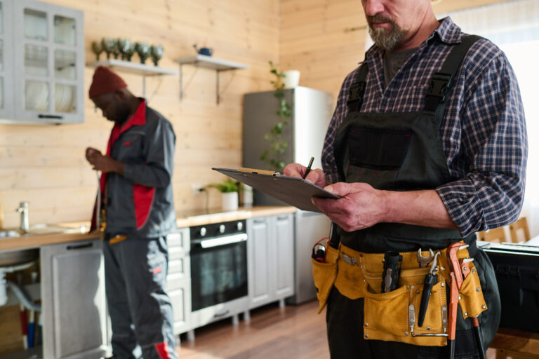 A professional home inspector examining the exterior of a house, taking notes on a clipboard during a property assessment.