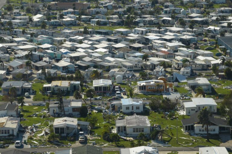 A residential neighborhood showing homes with visible hurricane damage, illustrating the impact of severe storms on property values.